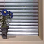 Silver Venetian blinds with pot plant on wide sill